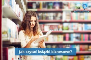 Młoda kobieta oparta o półkę z książkami przegląda książkę w twardej oprawie. Za nią też półki pełne książek. Księgarnia albo biblioteka